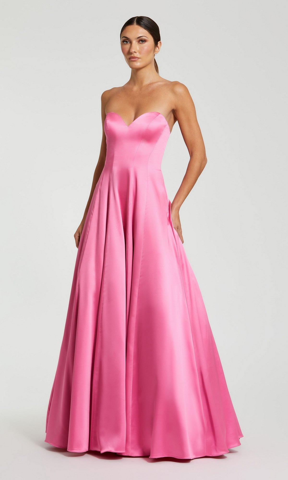 A woman stands against a plain background wearing the Mac Duggal 68857 long pink formal dress—a strapless satin gown featuring a fitted bodice and flared, floor-length skirt.